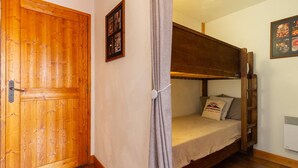 Een kamer met een houten deur, een stapelbed, een lijst met een afbeelding en een wandairconditioning.