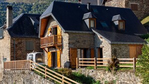 Un edificio de piedra con un balcón de madera, una escalera de piedra y vistas a un paisaje montañoso.