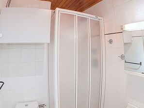 Ein Badezimmer mit Duschkabine, Toilette und Spiegel.