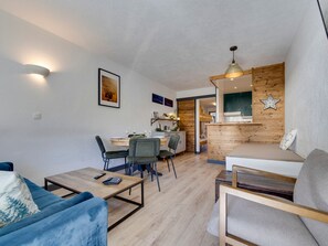 A modern living room with a sofa, a coffee table, and a dining area with chairs and a table.