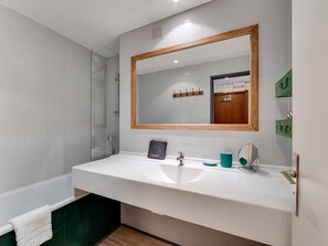 A modern bathroom with a white sink, a large mirror, and a glass shower enclosure.