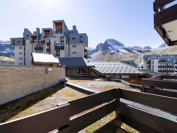 A modern building with multiple balconies and a mountainous backdrop.
