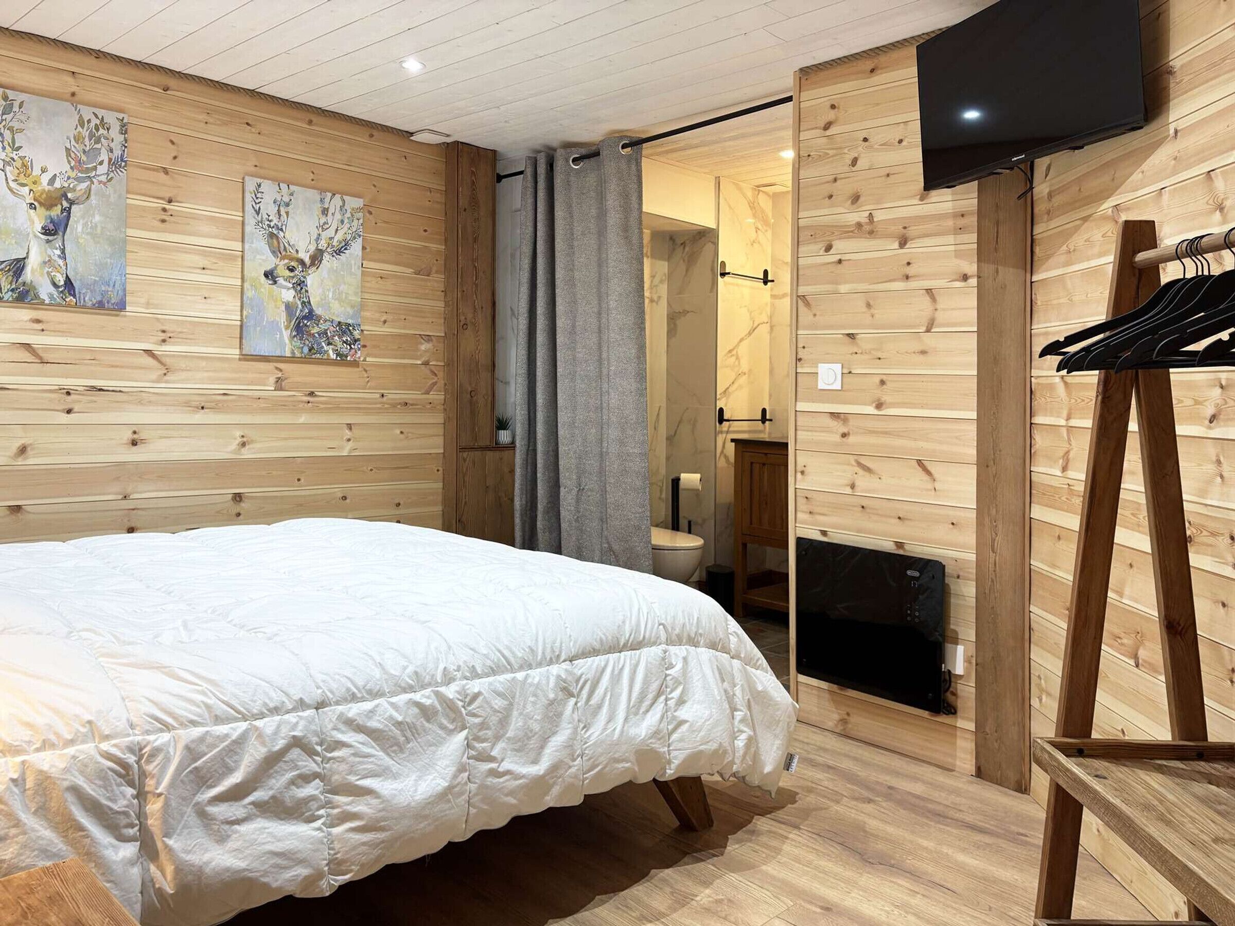 Een houten kamer met een bed, een televisie en een douche.