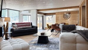 En moderne stue med sofa, lænestole, et sofabord og et spiseområde med stole.