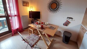A compact living space with a dining table, a television, and a small kitchen area. - Cozy studio for 3 with parking in Les Deux Alpes (Les Deux Alpes)