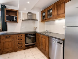 A kitchen with wooden cabinets, a stainless steel refrigerator, a dishwasher, and a microwave.
