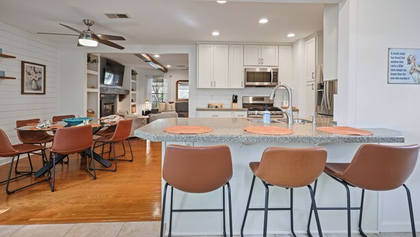 A modern kitchen with white cabinets, a granite countertop, and a central island with bar stools. - Lake Point Cottage at Acworth Beach (Acworth)