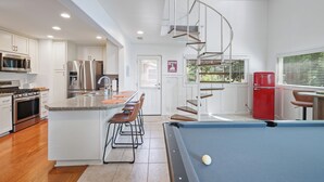 A modern kitchen with a pool table, a spiral staircase, and a red refrigerator. - Lake Point Cottage at Acworth Beach (Acworth)