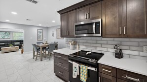 Una cocina moderna con armarios de madera oscura, microondas de acero inoxidable y estufa negra.