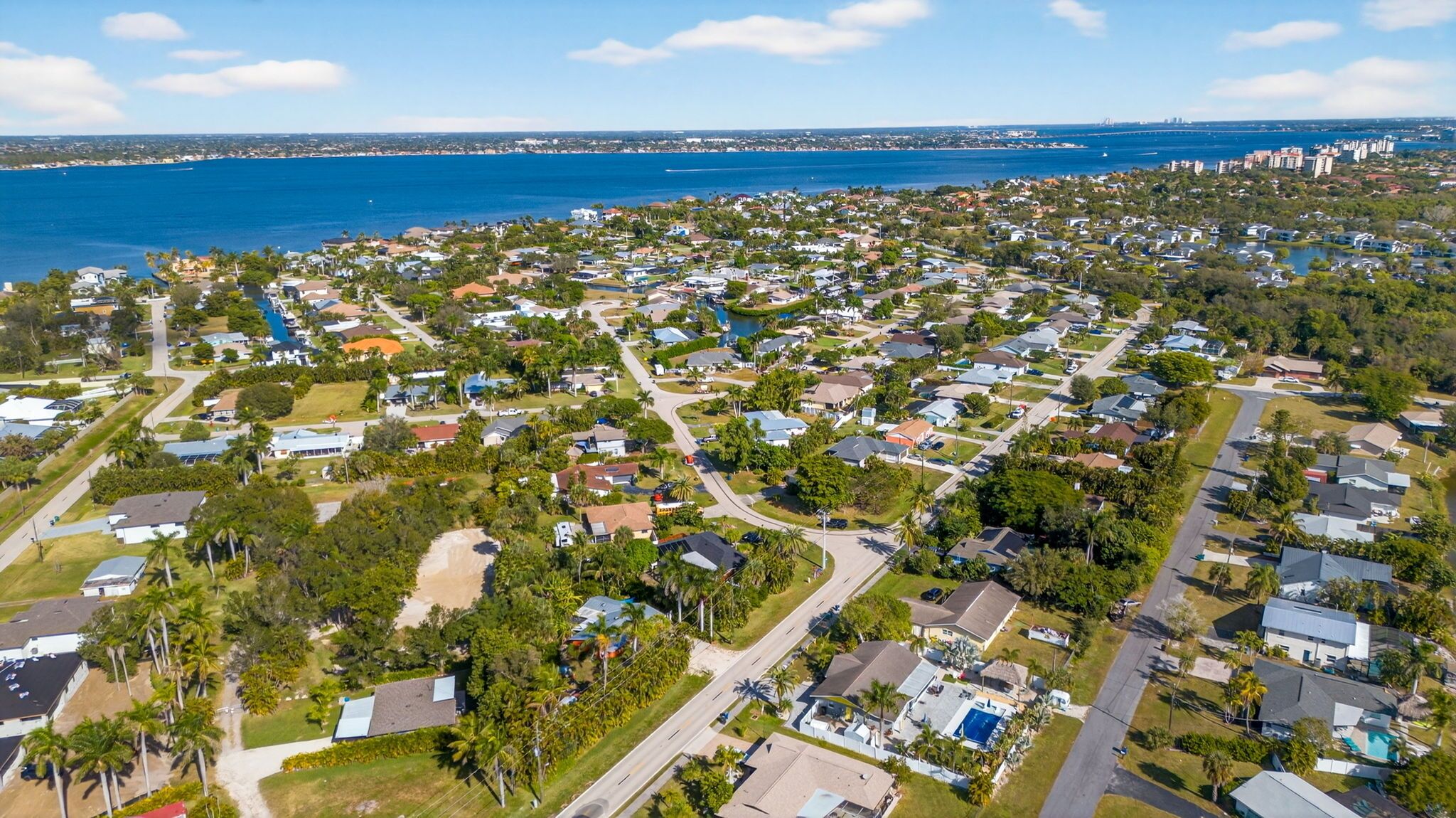 An aerial view of a residential area with houses, roads, and a large body of water in the background.