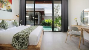 A modern bedroom with a large bed, a desk, and a view of a swimming pool and greenery.