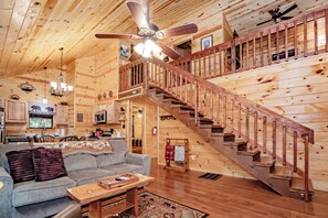 A wooden interior with a staircase, a sofa, and a dining area.