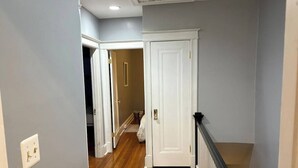 A hallway with wooden flooring, white doors, and a black railing.