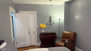 A bedroom with a bed, a dresser, a chair, a vase with flowers, and a lamp.
