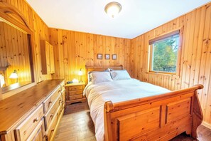 Une chambre à coucher aux murs lambrissés, avec un lit, une commode et des lampes de chevet.