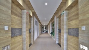 Un corridoio con pannelli di legno, porte numerate e pavimento tappezzato.