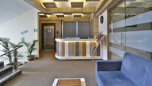 Un'area reception con un bancone, un divano blu, una scala e un segnale di uscita di sicurezza.