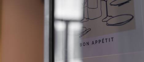 A framed artwork with the text 'BON APPÉTIT' and a line drawing of a person.