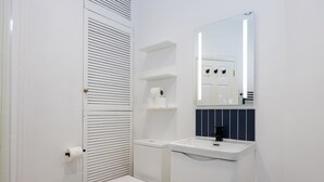 A small, white bathroom with a toilet, a sink, and a mirror. - Azure Suite 1BR (Greater Manchester)