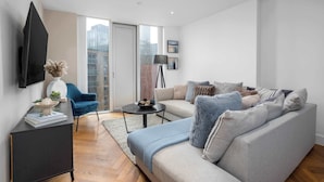 Ein modernes Wohnzimmer mit einer Couch, einem Couchtisch und einem an der Wand montierten Fernseher.