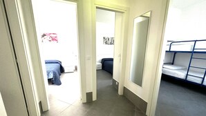 A hallway with a bunk bed on the right, a door leading to a bedroom, and a tiled floor. - Villa With Garden and Pool Access in Bibione (San Michele al Tagliamento)