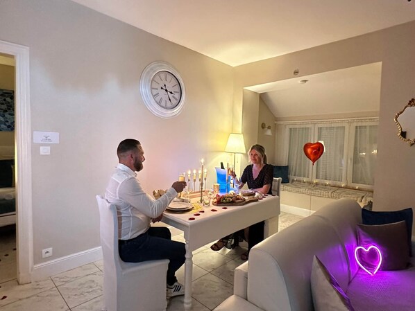 A dining area with a table set for two, candles, and a heart-shaped balloon.