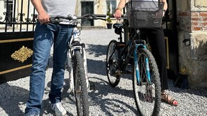 Een man en een vrouw staan naast fietsen voor een ijzeren hek.