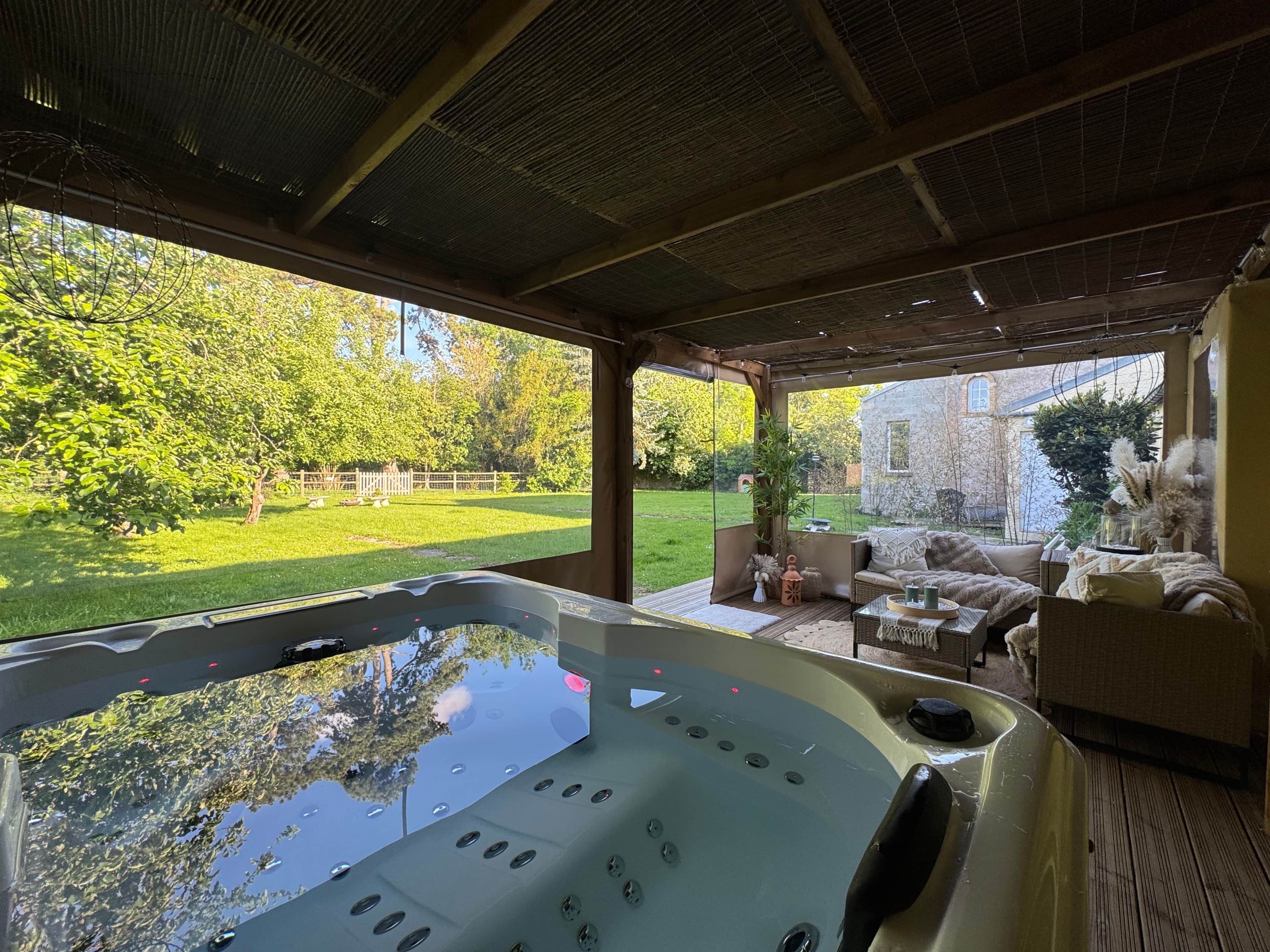 Un jacuzzi con vista a un jardín y un edificio de piedra al fondo.