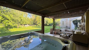 Un jacuzzi con vista a un jardín y un edificio de piedra al fondo.