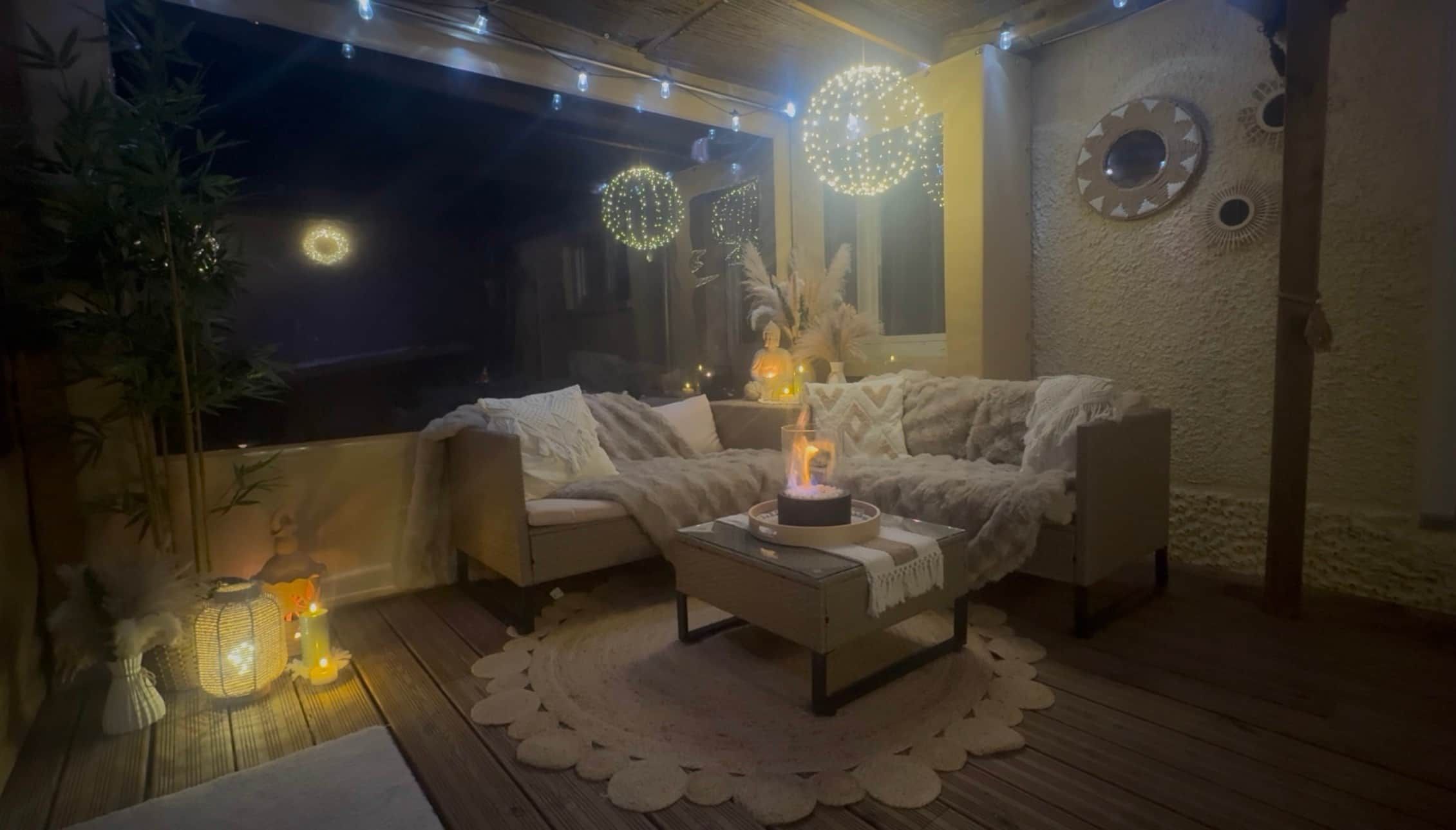 A cozy seating area with a sofa and chairs, a table with a candle, and decorative lights.