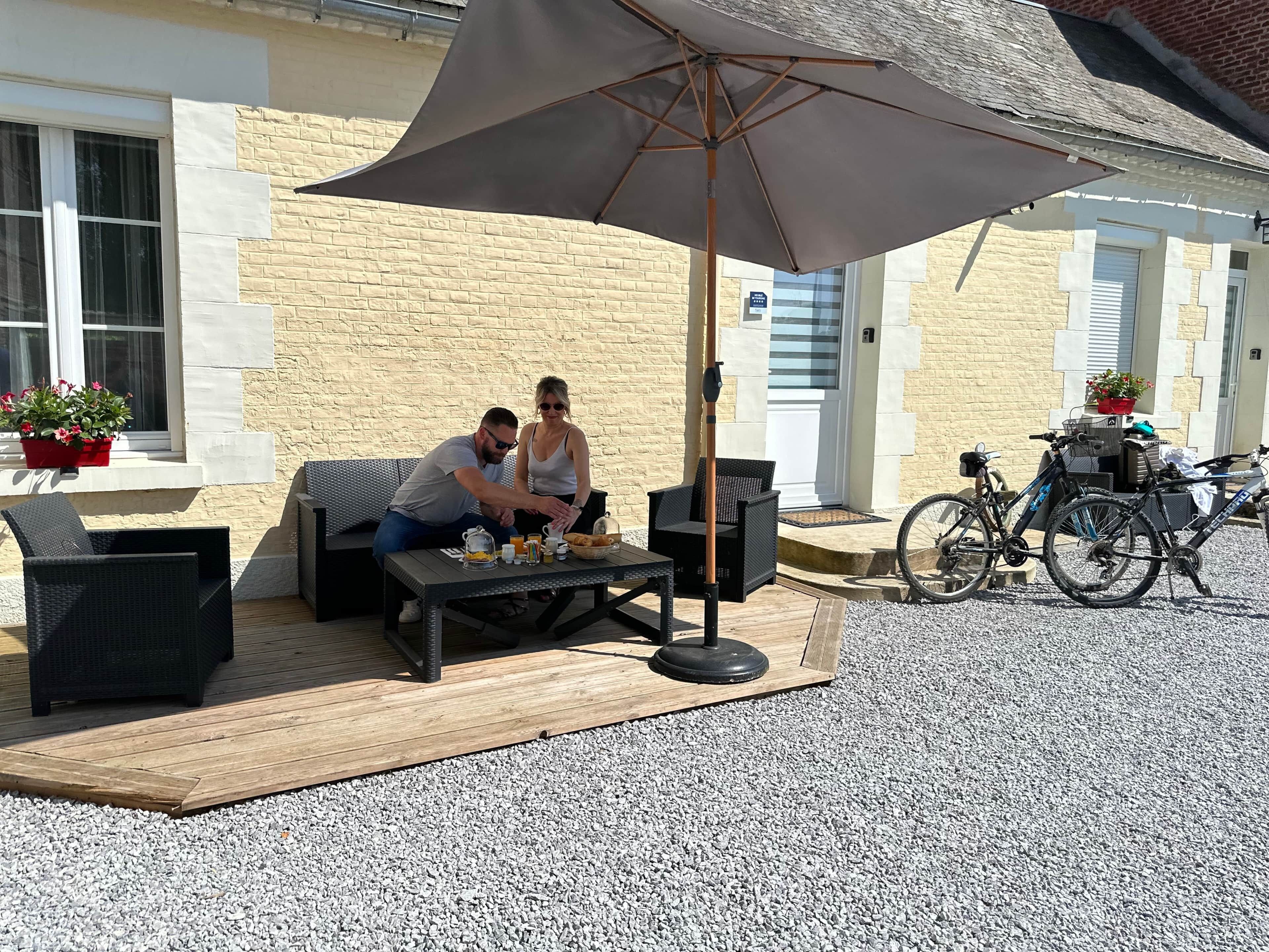A patio area with outdoor seating, a table with food and drinks, and a bicycle parked nearby.