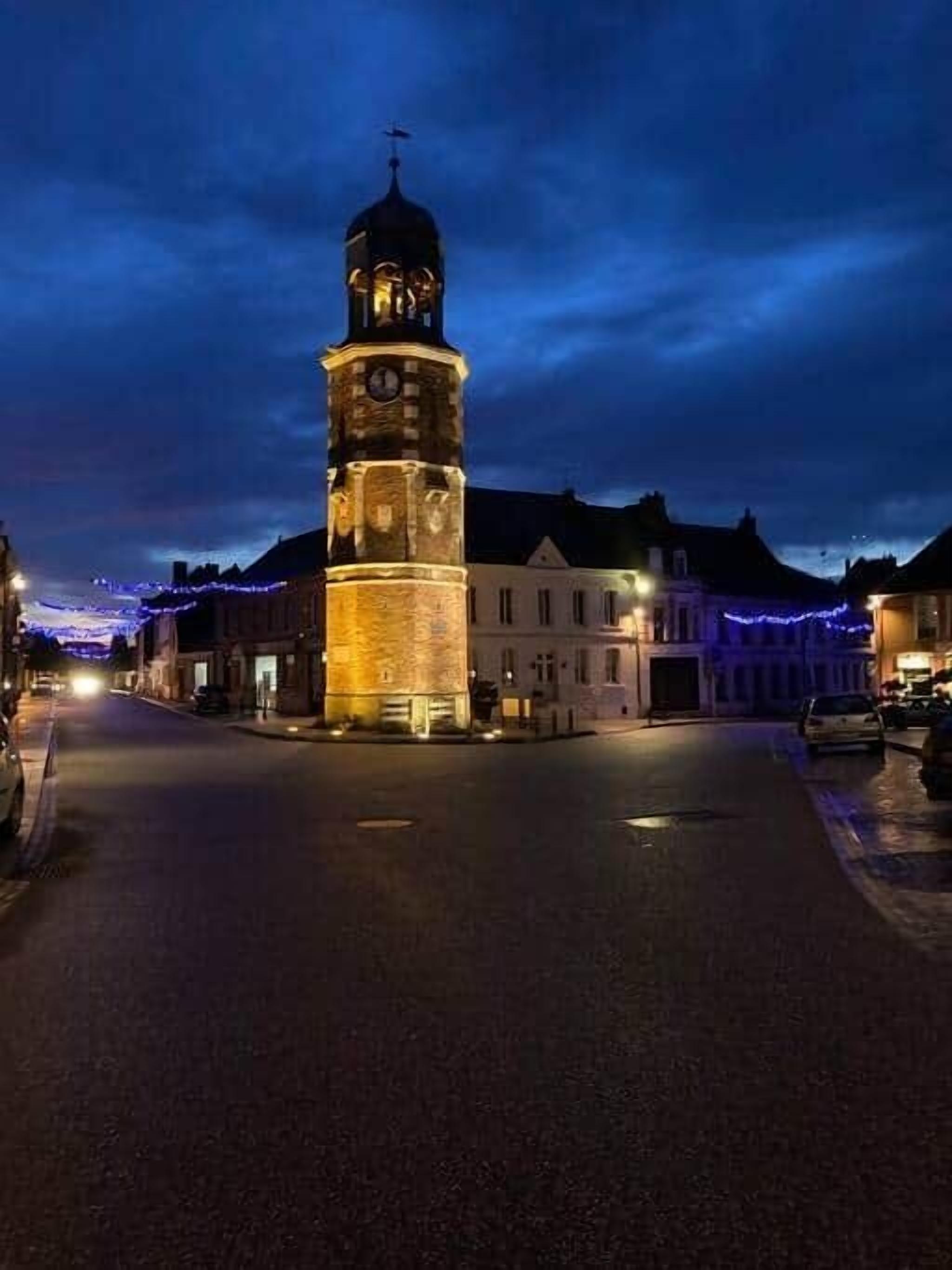 Een historisch uurwerk in een stadsplein, 's nachts.