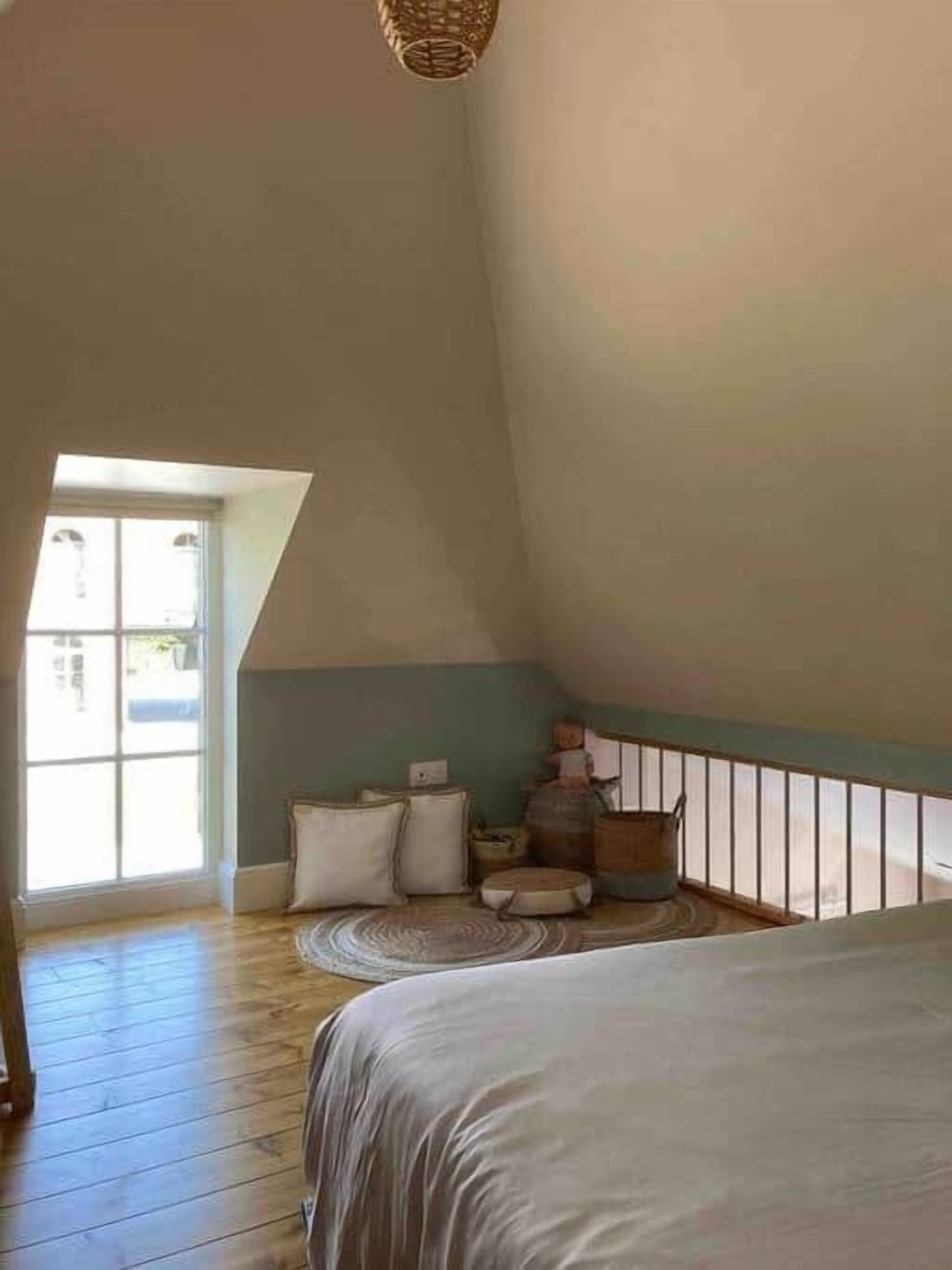 A bedroom with a sloped ceiling, a large window, and a view of the outside.