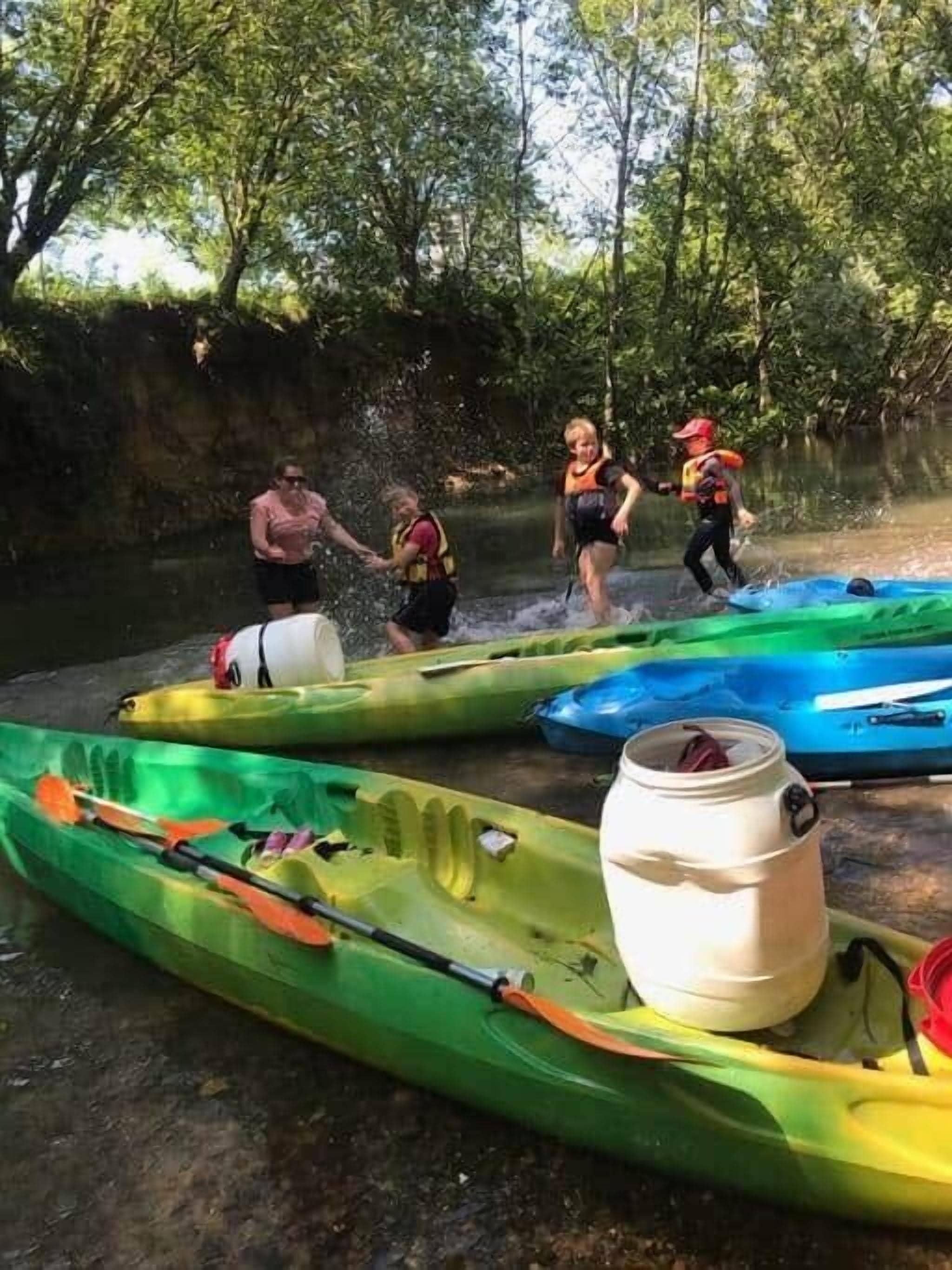 Un groupe de personnes en kayaks sur la rive d’une rivière, l’eau éclaboussant tout autour d’eux.