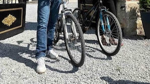 A man and a woman standing in front of a gated entrance with bicycles. - L’Agate bleue (suite) (Crécy-sur-Serre)