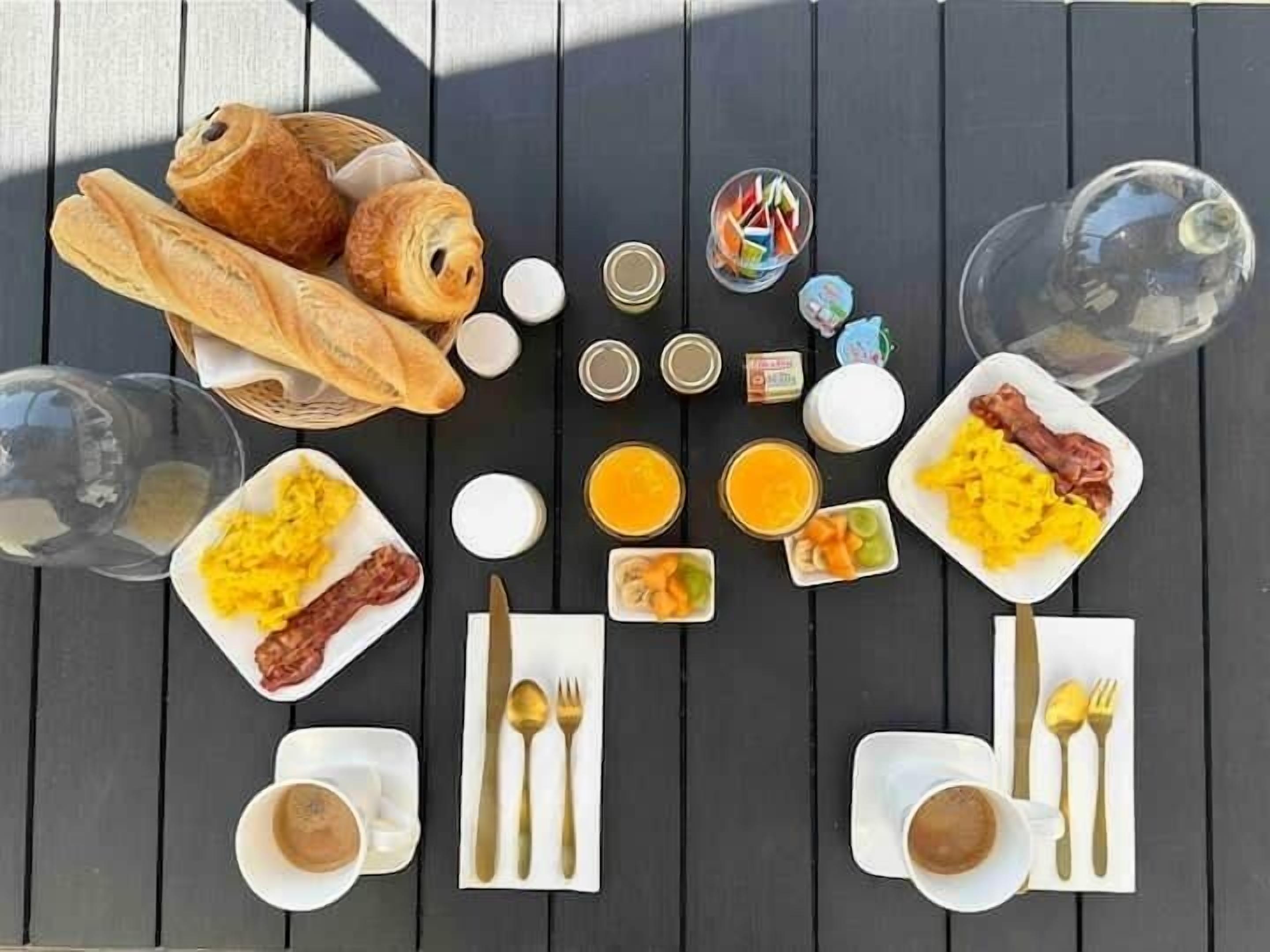 A breakfast table with various food items, including eggs, toast, and beverages.
