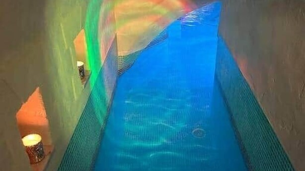 An ice tunnel with a blue-lit water feature and a tiled floor. - L’Agate bleue (suite) (Crécy-sur-Serre)