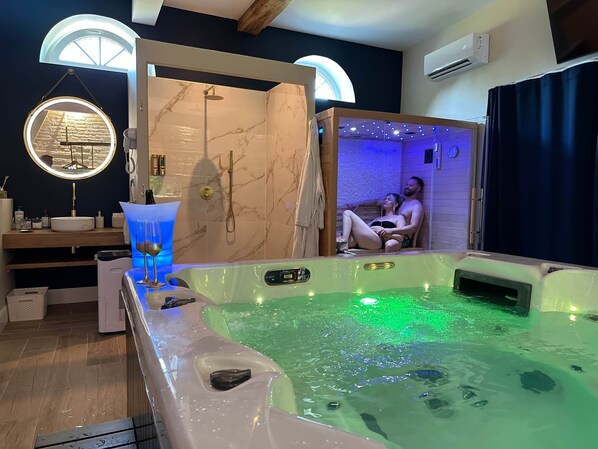Une salle de spa équipée d’un bain à remous, d’un espace douche et d’une coiffeuse avec un miroir.