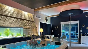 A modern room with a hot tub, a large fish tank, and a cozy seating area. - La bulle LOVE (chauffée) Au Domaine Du Pré Dieu (Crécy-sur-Serre)