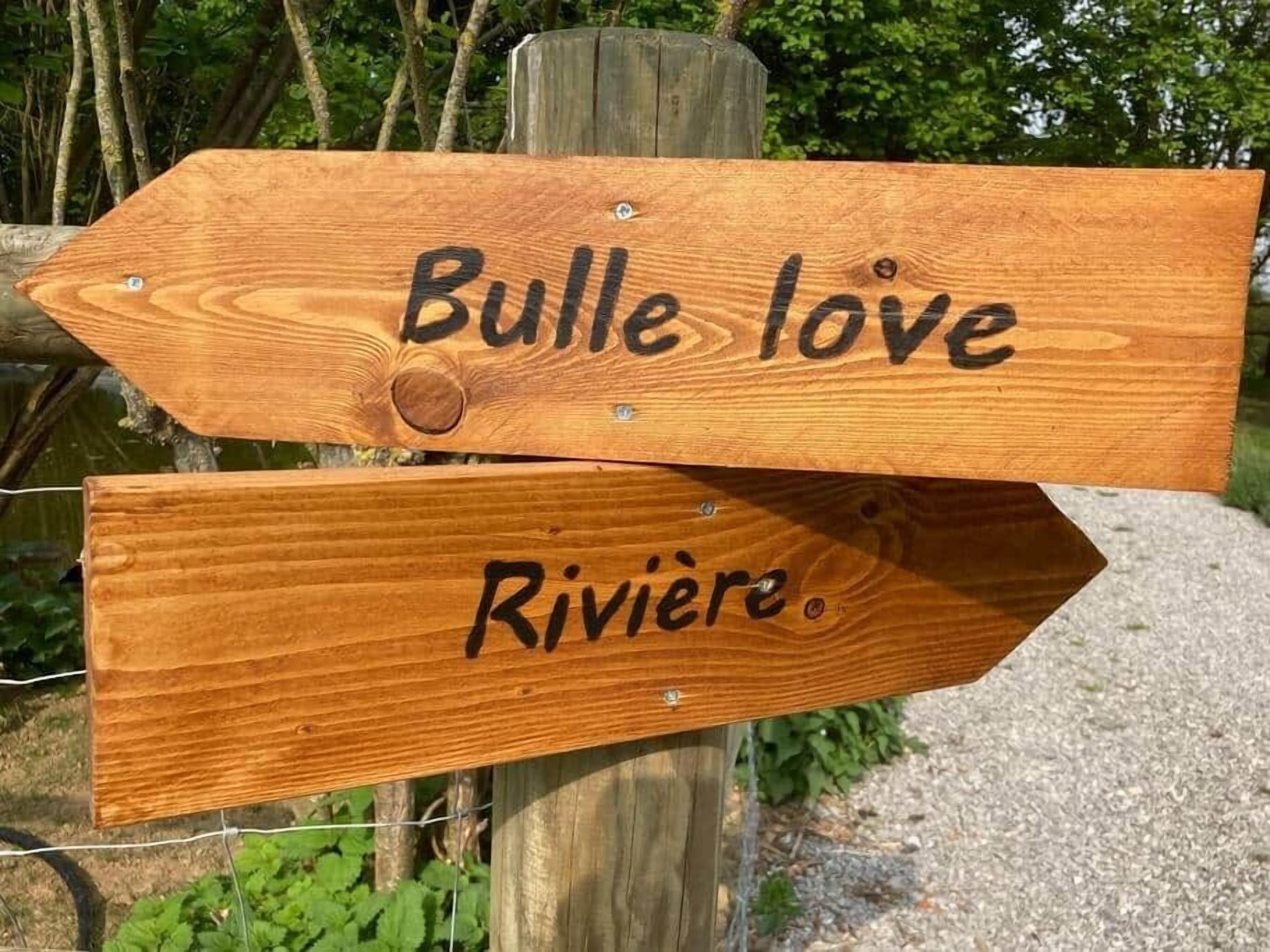Un segnale direzionale in legno con due indicazioni: una verso 'Bulle love' e l'altra verso 'Riviere'.