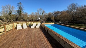 Eine Holzterrasse mit Pool, Liegestühlen und einem Holzzaun.