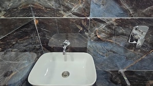 A bathroom with a white sink, black marble tiles, and a window. - Hotel Nexon Inn (Ahmedabad)