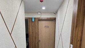 A hallway with marble flooring, wooden walls, and a door labeled "Restroom & Pantry". - Hotel Nexon Inn (Ahmedabad)