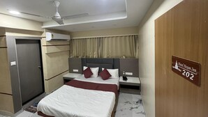 A hotel room with a bed, a nightstand, a desk, a wardrobe, a ceiling fan, and a sign indicating the room number 202. - Hotel Nexon Inn (Ahmedabad)