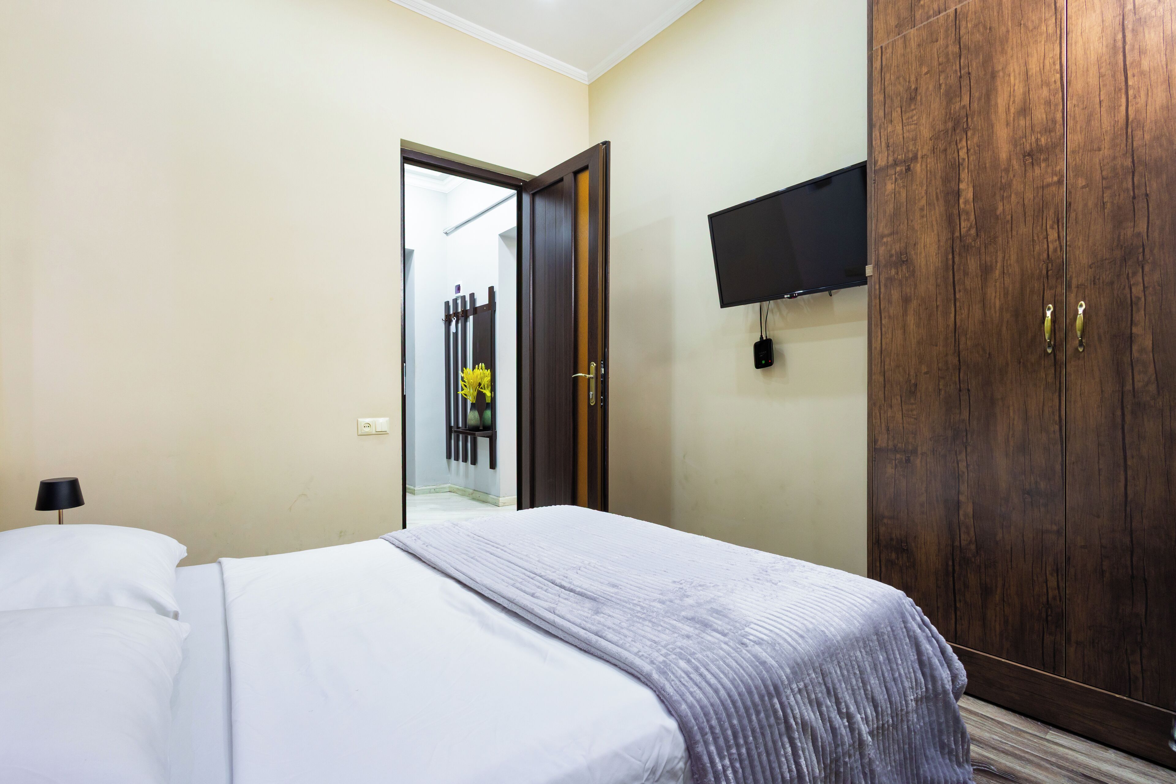 Een hotelkamer met een bed, een kledingkast en een aan de muur bevestigde televisie.