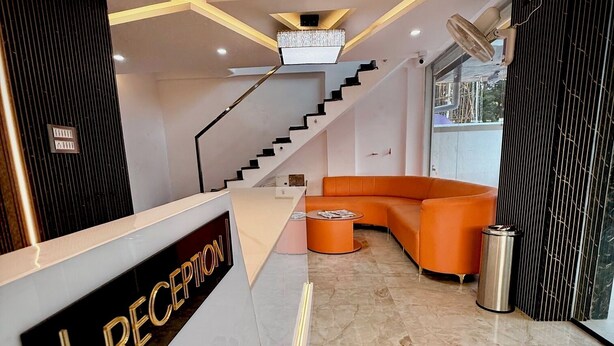 A reception area with a staircase, a reception desk, and a seating area. - AR signature Inn (Mysore)