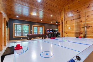 An indoor ice hockey rink with a pool table, arcade games, and a wooden interior.