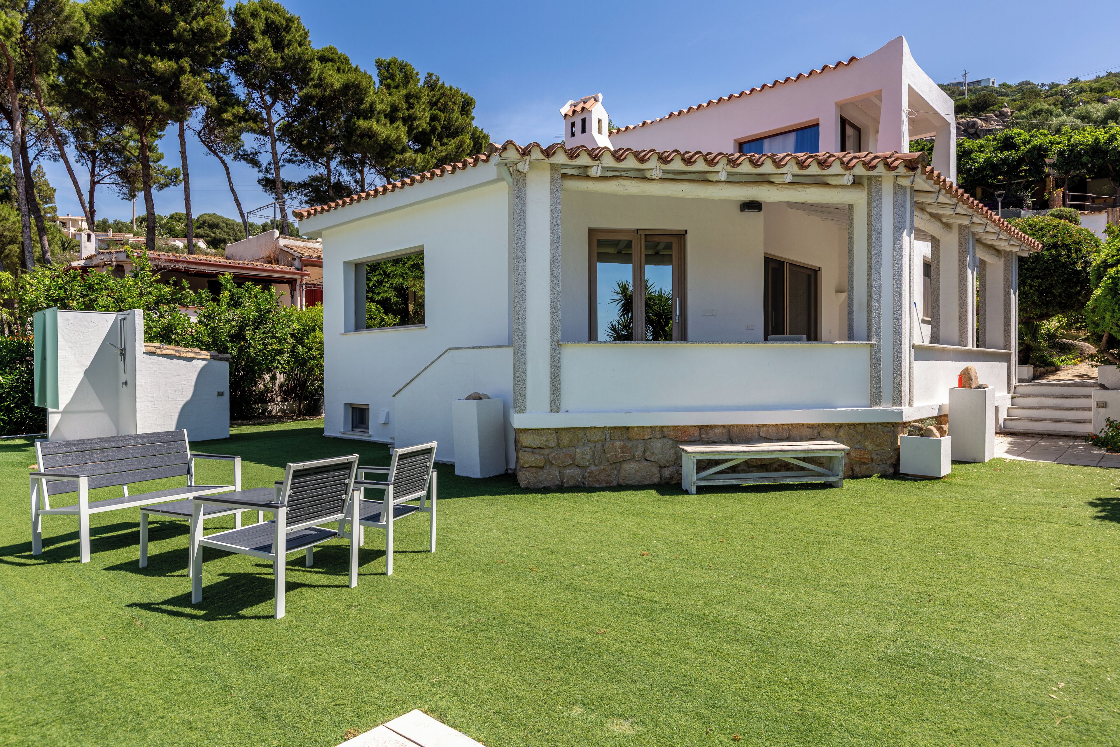 Ein modernes Haus mit Terrasse, einer Steinmauer und einem kleinen Pool.