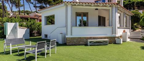 Ein modernes Haus mit Terrasse, einer Steinmauer und einem kleinen Pool.