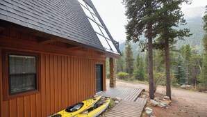 Eine Holzhütte mit einer Terrasse und zwei geparkten Kajaks.